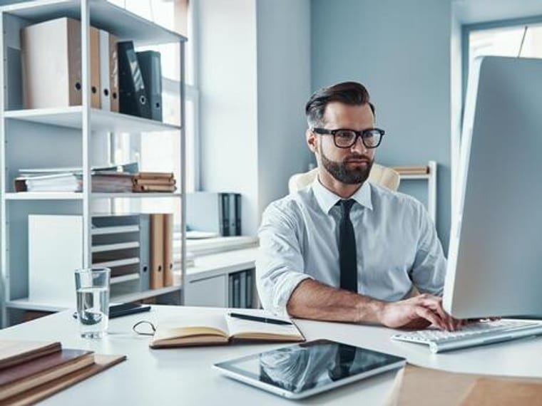 Consultant reviewing tender submissions and project documents at his desk
